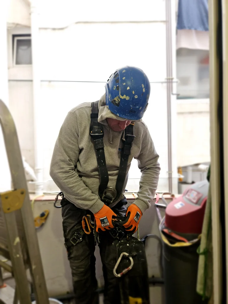 Trabajador de construcción ajustando su equipo de seguridad antes de realizar trabajos verticales.