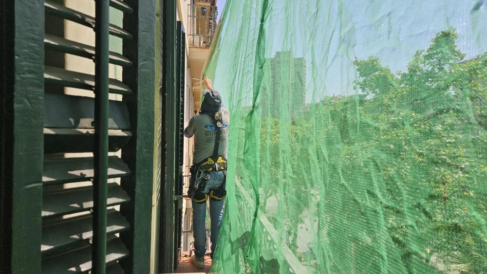 reparación de balcones en Barcelona con operario instalando una red de protección durante la rehabilitación