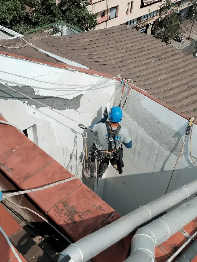 Técnicos de trabajos verticales en Barcelona realizando reparación de bajantes y fachada.