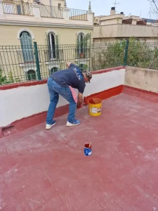 alt="Técnico sellando filtraciones en cubierta de edificio"